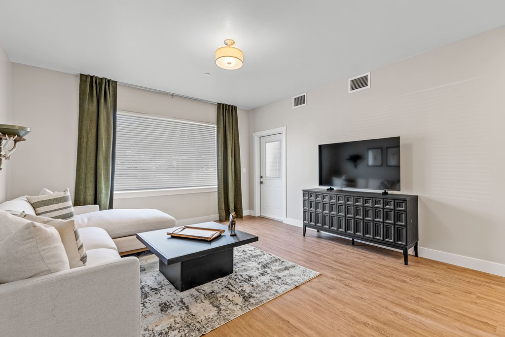 A living room with a white couch, a black coffee table, and a flat screen TV.
