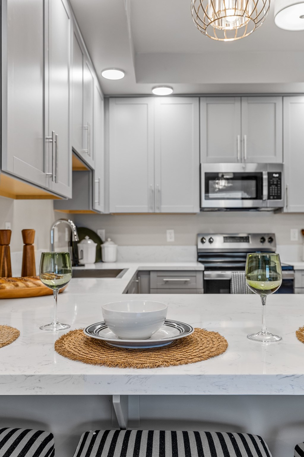 A modern kitchen with a marble countertop and striped stools.