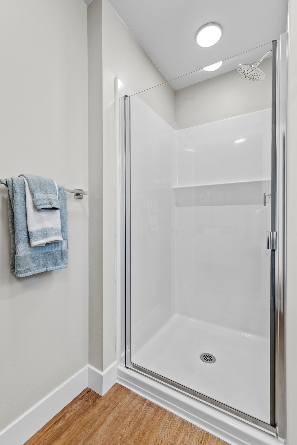 A blue towel hangs on a white wall in a white bathroom.