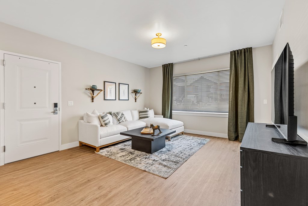 A living room with a white couch, a coffee table, and a flat screen TV.