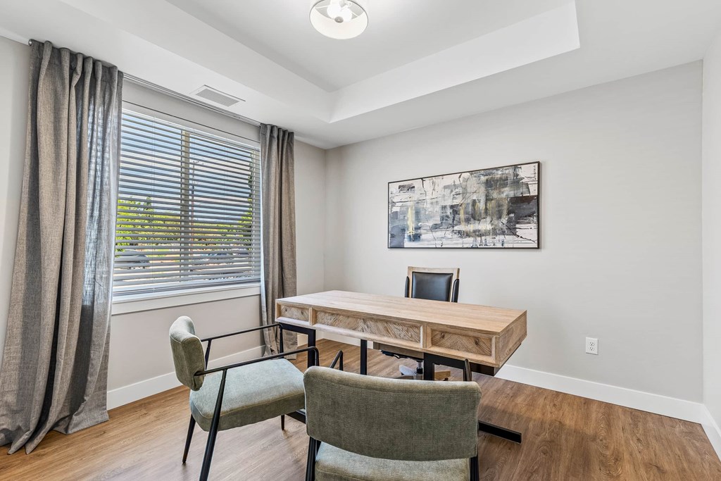 A room with a table and chairs and a painting on the wall.