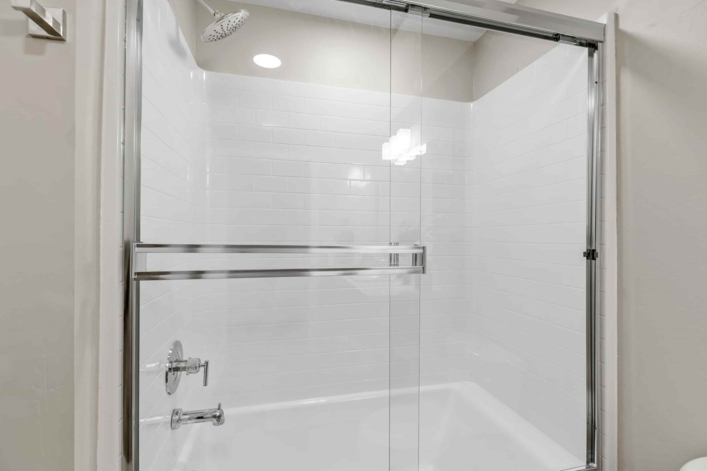 A glass shower door with a handle and a glass shelf.