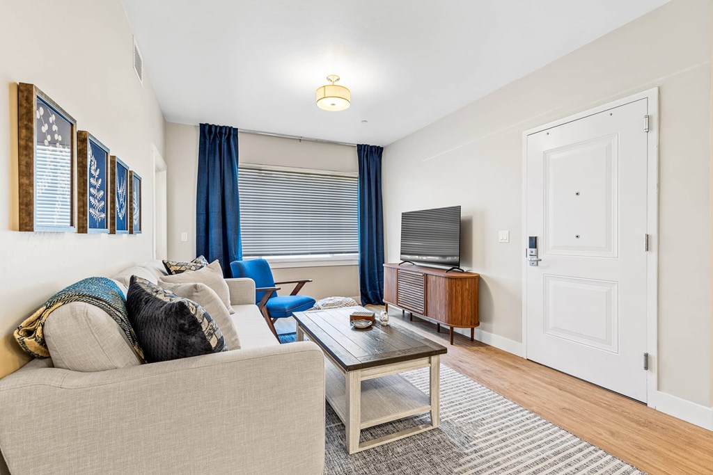 A living room with a beige couch, a coffee table, and a television.