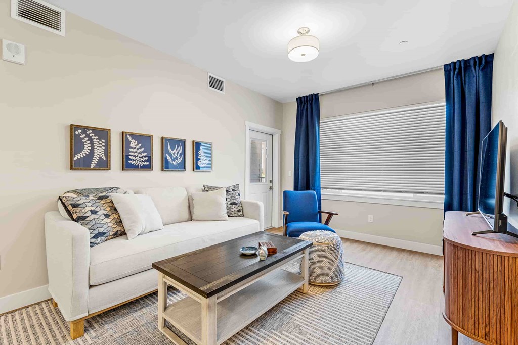 A living room with a white couch, a coffee table, and a blue chair.