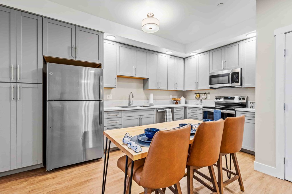 A kitchen with a table and chairs in front of a refrigerator.