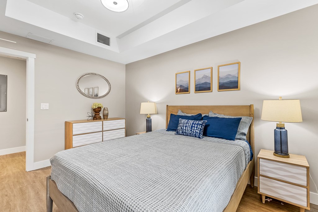 A bedroom with a bed, nightstands, and pictures on the wall.