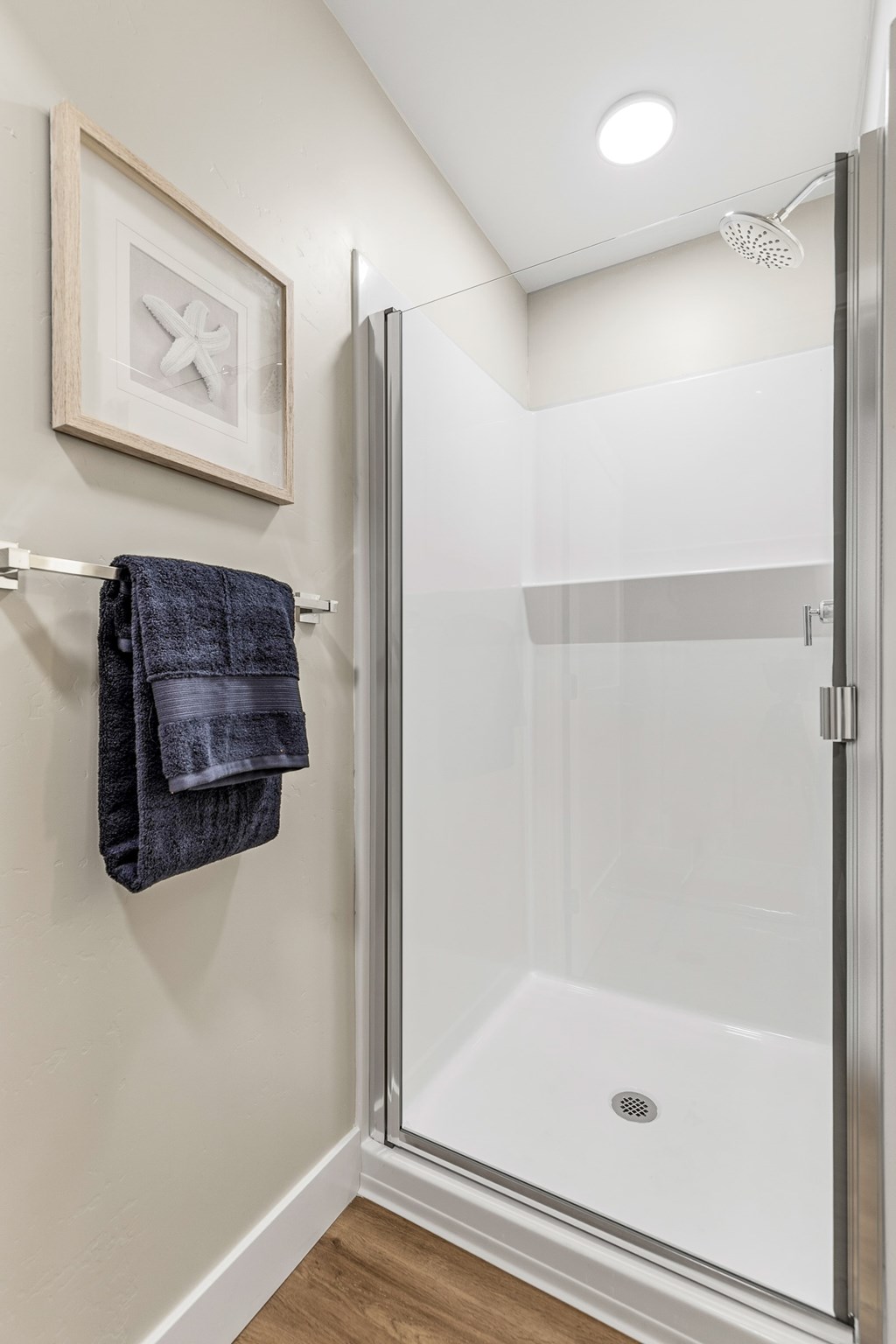 A bathroom with a glass shower door and a towel hanging on the wall.