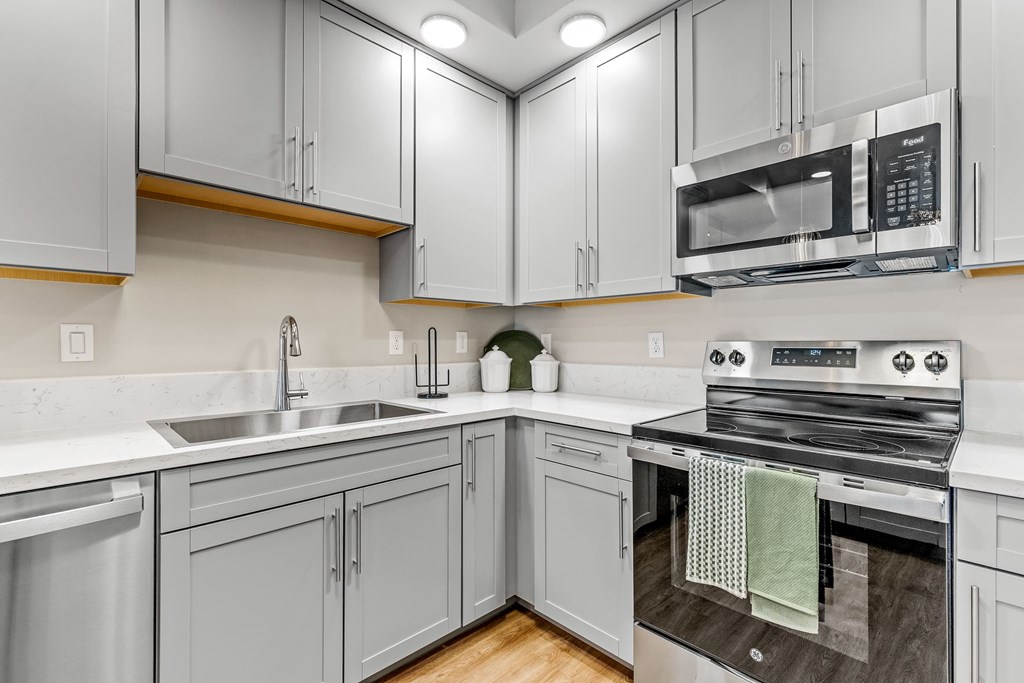 A kitchen with a stove, sink, and cabinets.