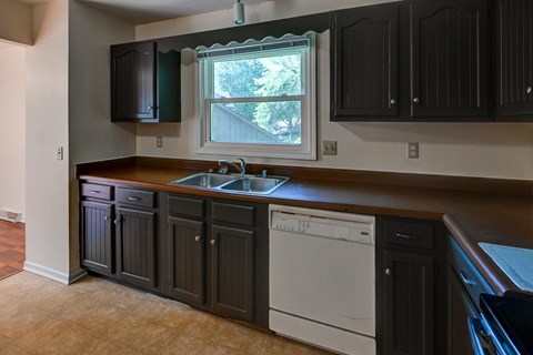A kitchen with dark brown cabinets and a white dishwasher.
