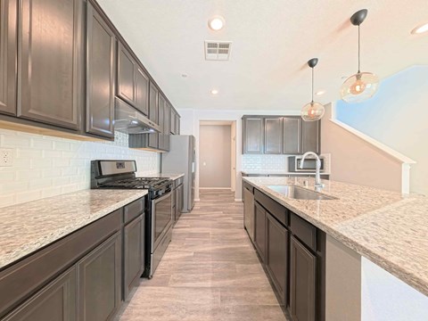 A kitchen with dark brown cabinets and a white backsplash.
