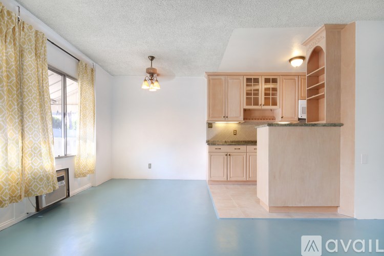 A room with a kitchen area in the background and a living room in the foreground.