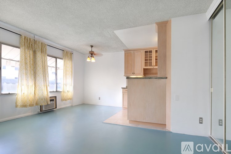 A room with a window, curtains, and a wooden cabinet.