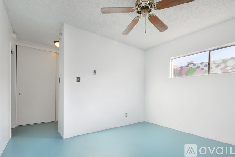 A room with a ceiling fan and a window with a view of a colorful mural.