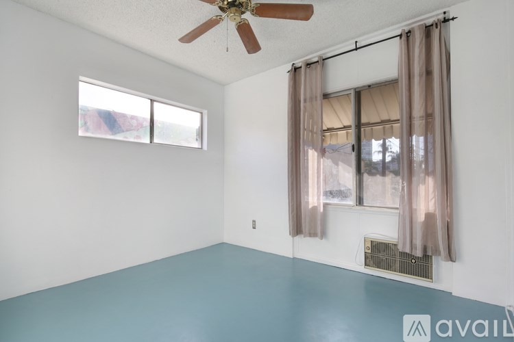 A room with a ceiling fan and a window with curtains.