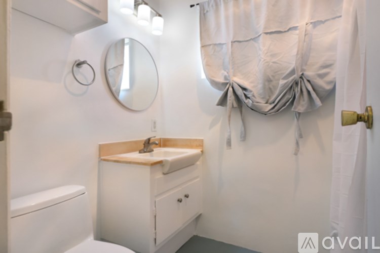 A bathroom with a white sink and a round mirror on the wall.