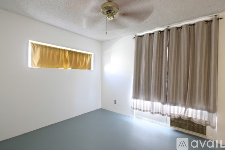 A room with a ceiling fan and a window with curtains.