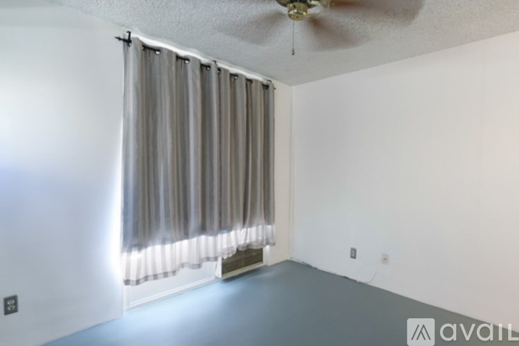 A room with a fan, window, and curtains.