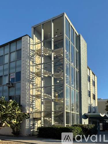A tall building with a glass facade and a tree in front of it.