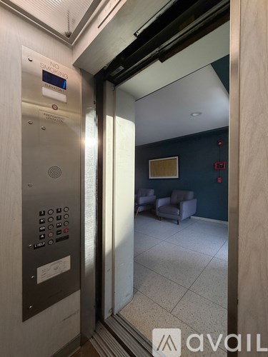 A modern elevator with a control panel and a mirrored wall in the background.