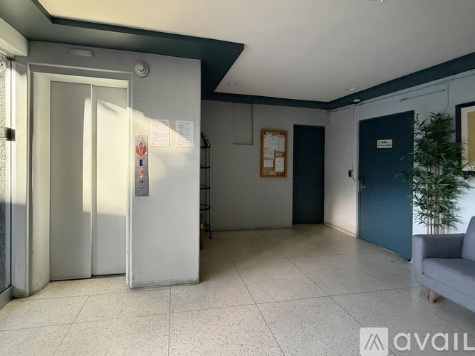 A room with a white tiled floor and a grey sofa.