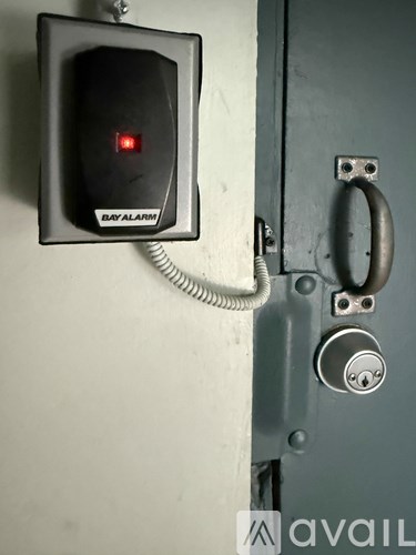 A bay alarm device is mounted on a wall next to a door.