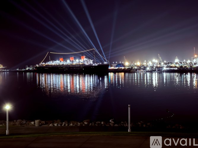 A large ship is docked at a pier, illuminated by bright lights.