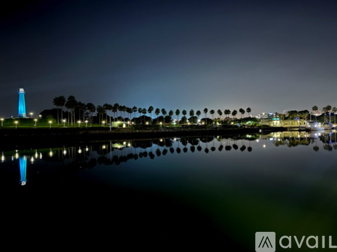 A lighthouse stands tall near a body of water, with its reflection visible on the surface.