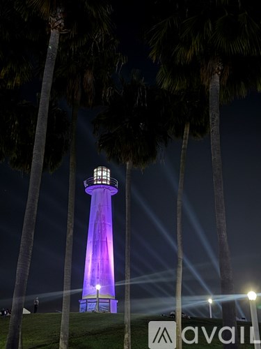 A lighthouse is lit up with purple lighting at night.