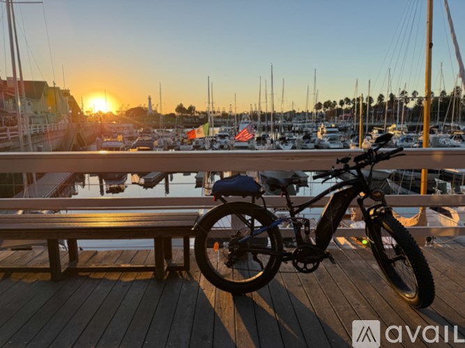 A bicycle is parked on a wooden dock with boats in the background during sunset.