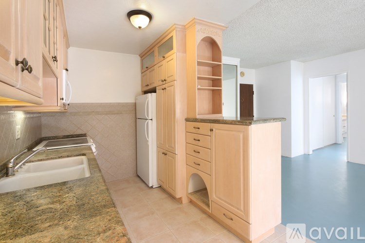 A kitchen with a sink, refrigerator, and cabinets.