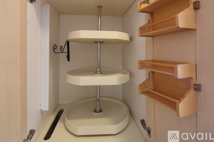A white cake stand on a table in a cabinet.