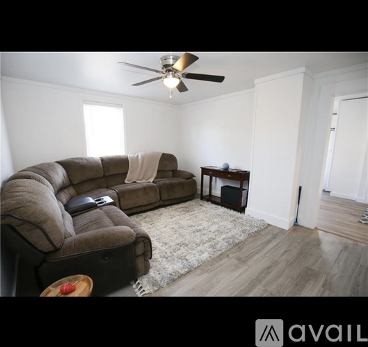 A living room with a brown couch and a ceiling fan.
