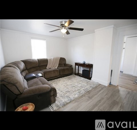 A living room with a brown couch and a ceiling fan.
