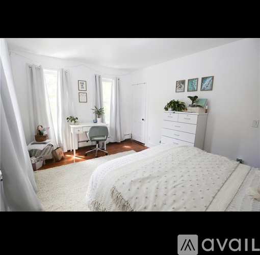 A bedroom with a large bed and a dresser with plants on top.