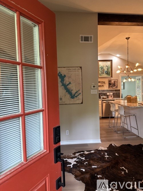 A red door with a black handle and a cowhide rug in front of it.