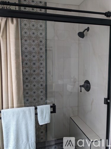 A bathroom with a glass shower door and a towel hanging on the side.