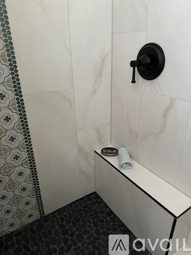 A white bathtub with a black faucet and a black and white tiled floor.
