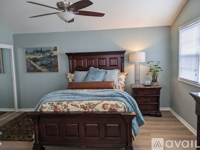 A bedroom with a large bed and a ceiling fan.