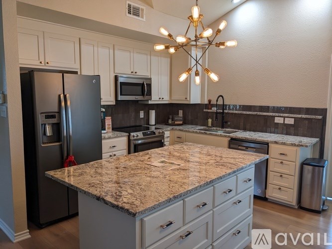 A kitchen with granite countertops and a black refrigerator.