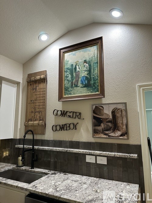 A kitchen with a marble counter top and a framed picture of a cowboy.