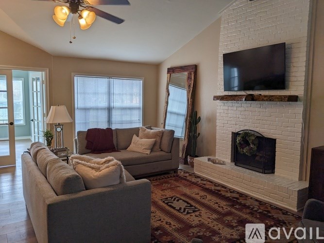 A living room with a fireplace and a television mounted above it.