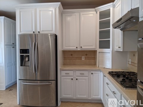 A kitchen with white cabinets and a stainless steel refrigerator.