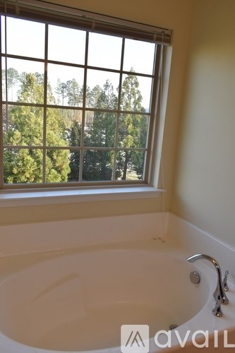 A bathroom with a tub and a window overlooking trees.