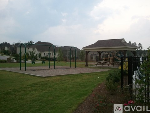 A playground with a swing set and a gazebo-like structure in the background.