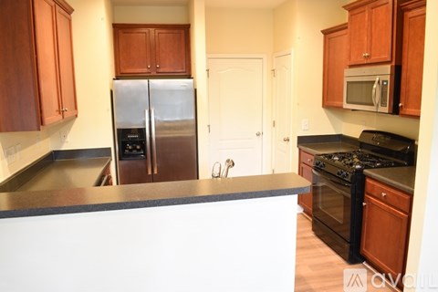 A kitchen with wooden cabinets and a stainless steel refrigerator.