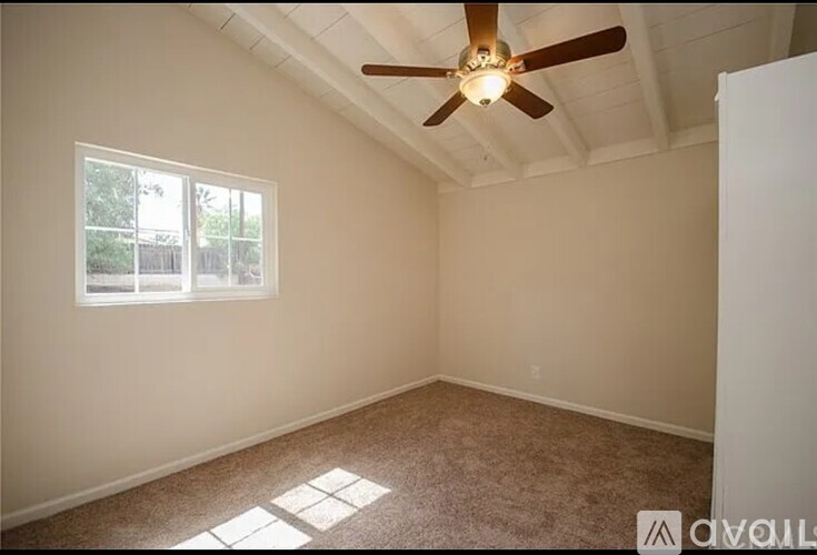 A room with a ceiling fan and a window.