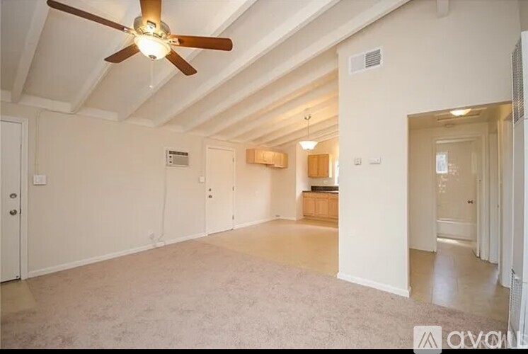 A spacious room with a ceiling fan and carpeted floor.