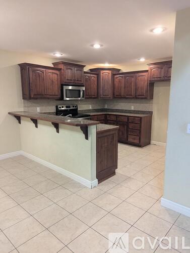 A kitchen with brown cabinets and a tiled floor.
