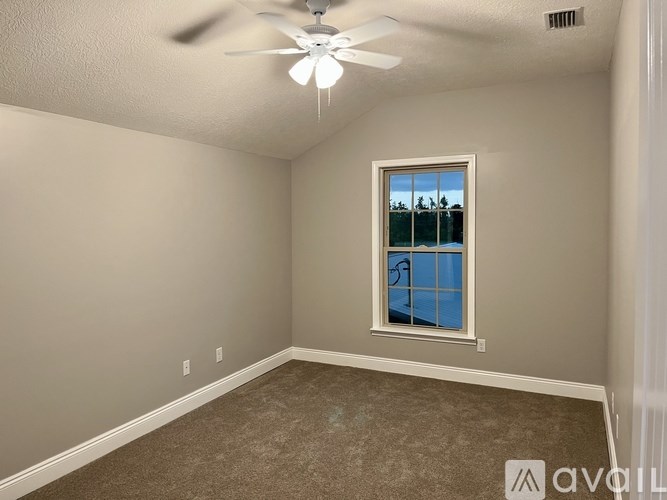 A room with a ceiling fan and a window showing a pool and trees outside.