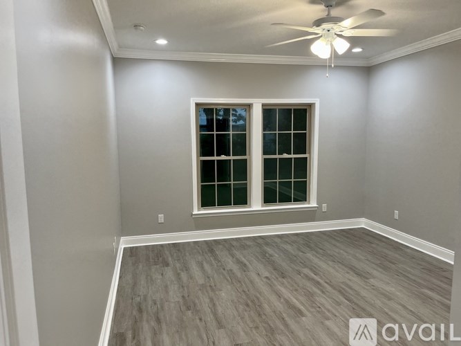 A room with a ceiling fan and a window with a view of trees outside.